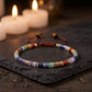 Pulsera Alineación 7 Chakras sobre una piedra oscura con velas al fondo