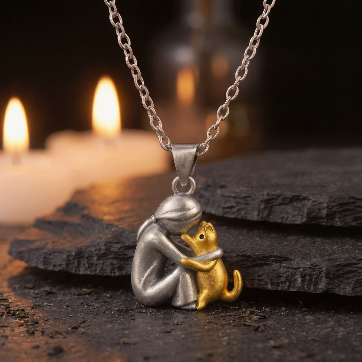 Collar Lazo Eterno, diseño mujer abrazando a su gato, sobre una piedra oscura con velas al fondo