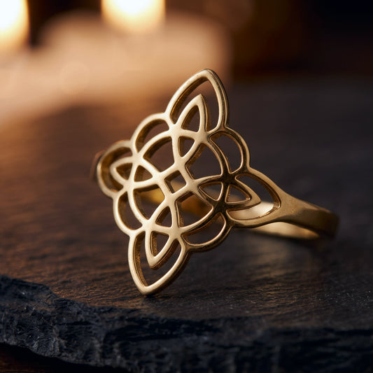 Anillo Nudo de Bruja en color dorado sobre una piedra oscura, con velas encendidas al fondo