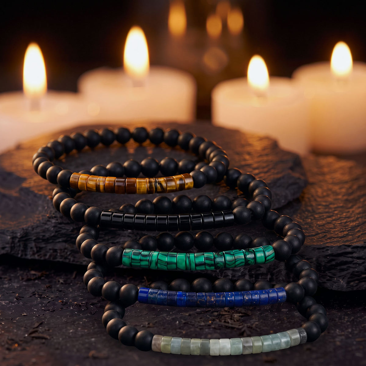 Las cinco Pulseras Sutiles con Propósito juntas sobre una piedra oscura con velas